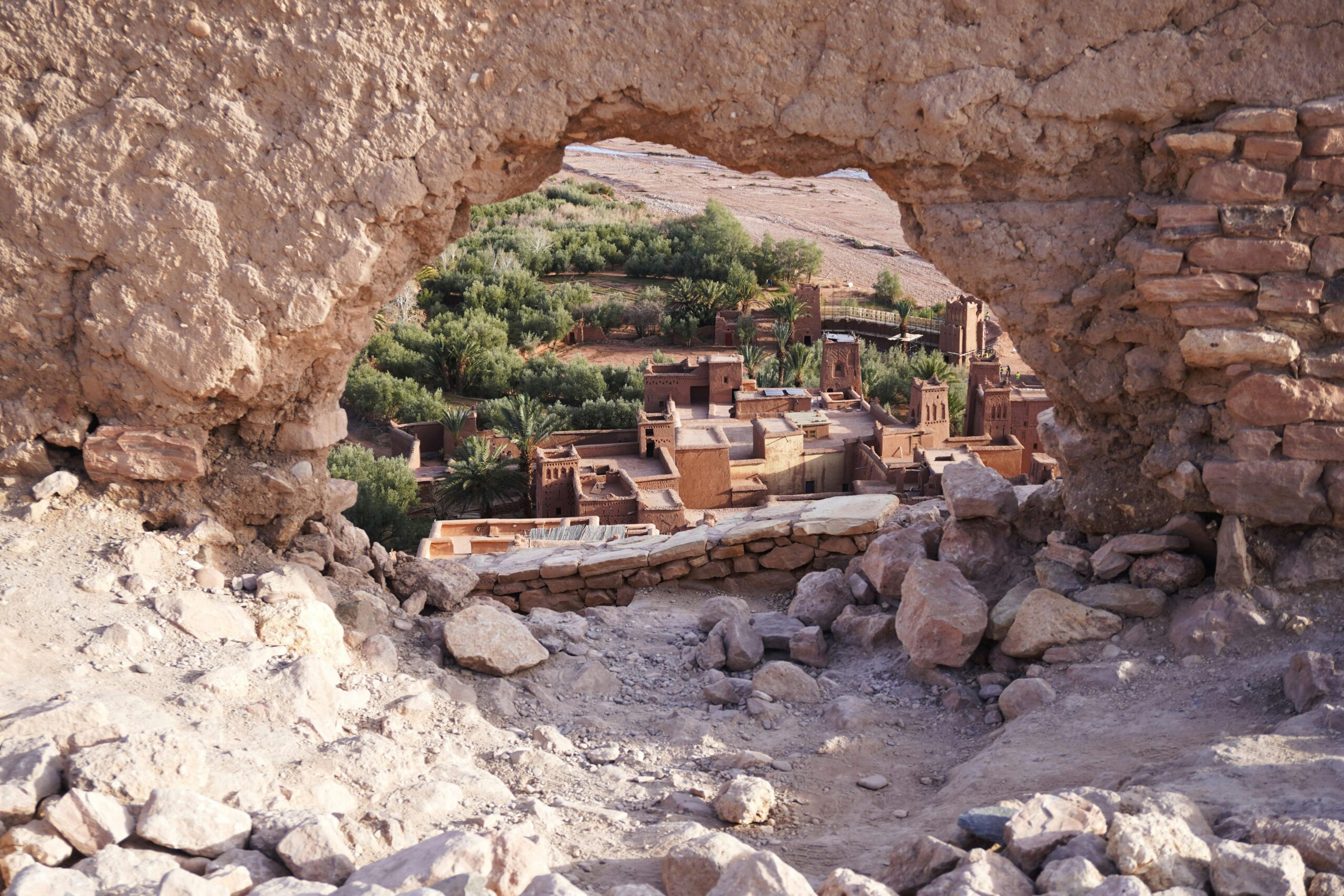 A picturesque view of Aït-Ben-Haddou through ancient ruins, showcasing Morocco's desert architecture.