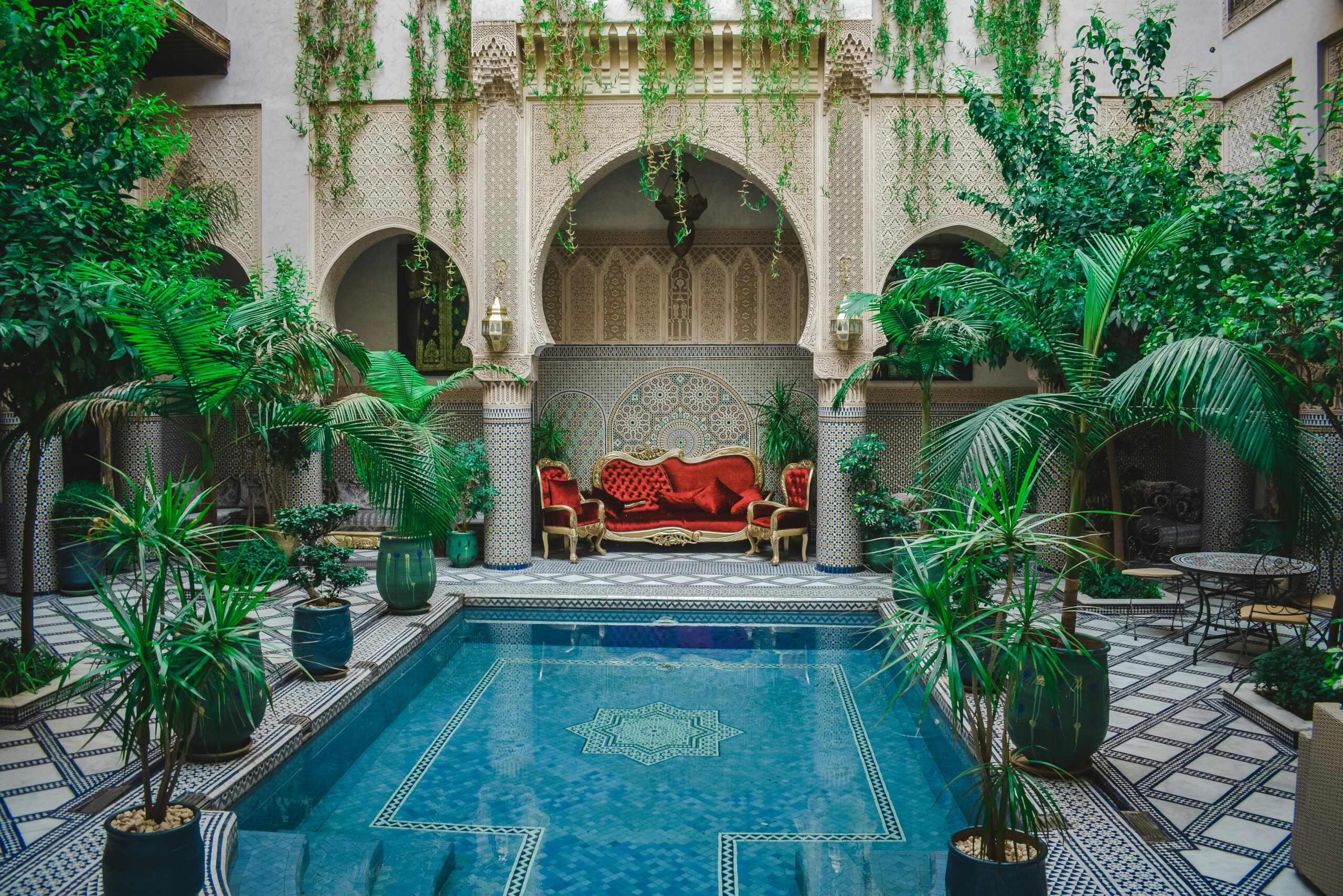 Elegant Moroccan courtyard featuring lush greenery and a decorative pool, perfect for a serene escape.