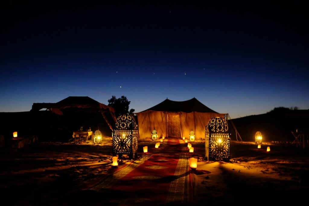 Luxury desert camp in the Morocco Sahara at night with traditional lanterns